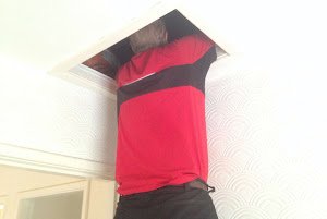 "man squeezing through small loft hatch"